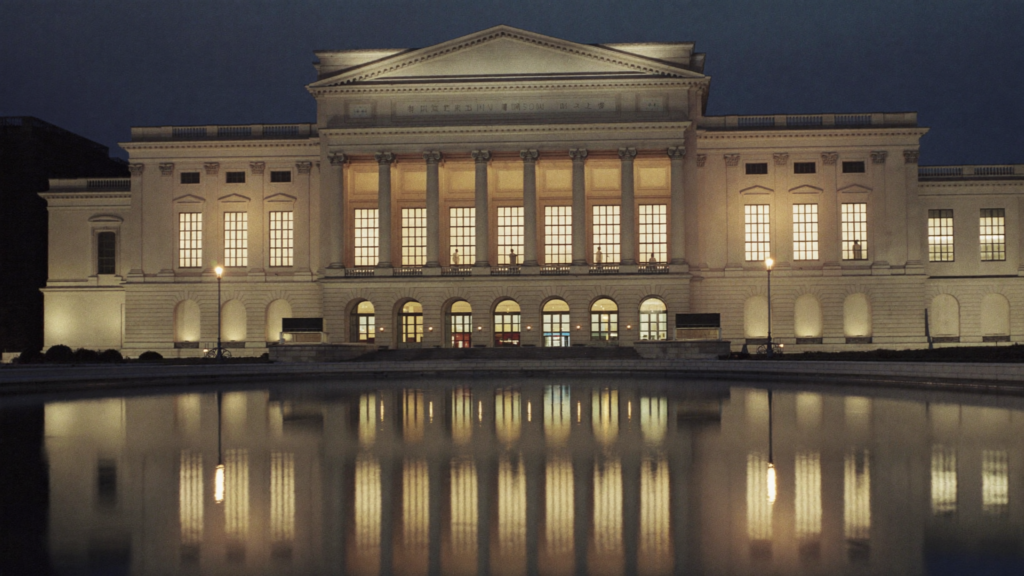 A grand cultural institution illuminated at dusk and mirrored in a reflecting pool, evoking soft power and nation brand.